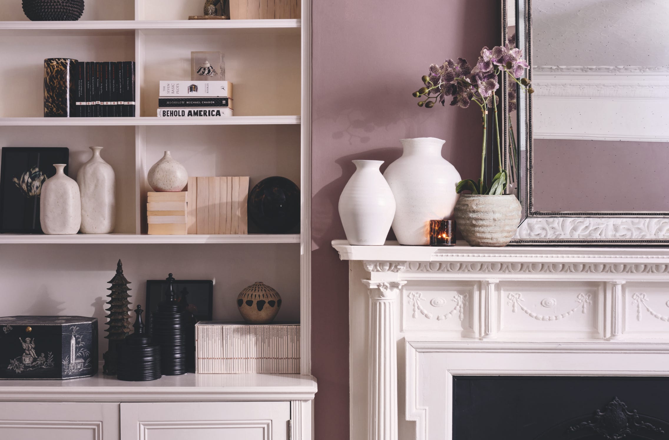 White shelves with monochrome décor, next to a white mantelpiece