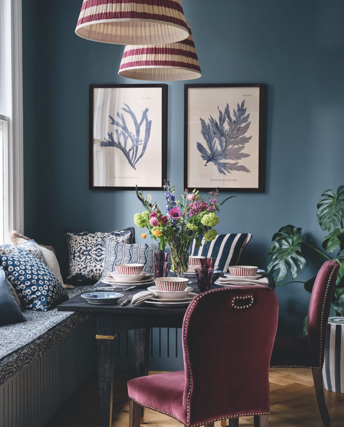 A colorful dining room with red Stafford chairs and a blue bench seat