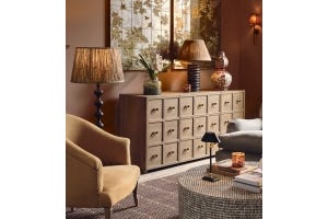 A cosy sitting room with a yellow armchair and wooden sideboard