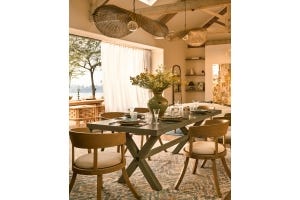 A yellow dining room with plants on the table.