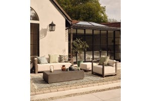 An outdoor lounge area including a sofa and armchair, coffee table, outdoor rug and decor.