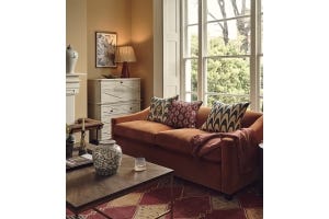 A cozy fall sitting room featuring an orange velvet sofa decorated with patterned pillows.