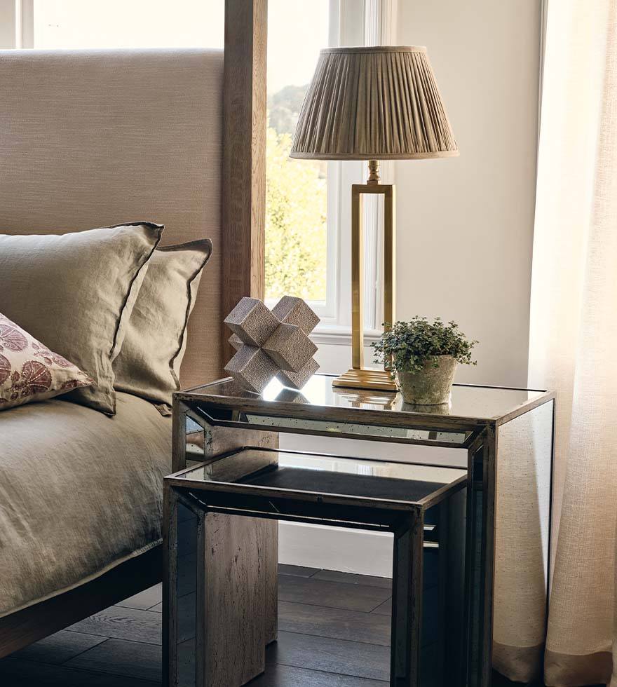 A mirrored nightstand with a gold metal table lamp