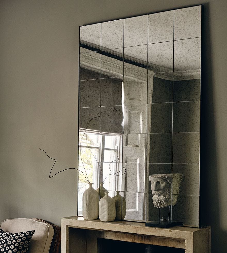 A large rectangular mirror with grid-style detailing sits on a console table.