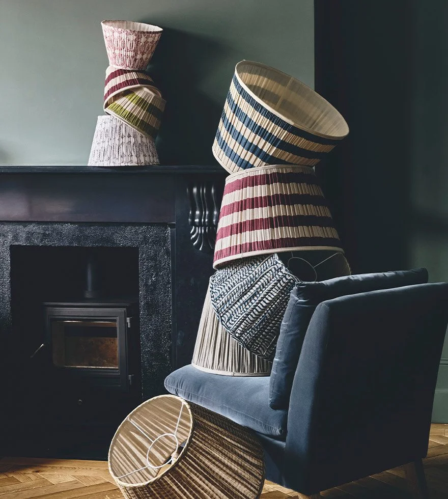 A bright cottage sitting room with a cosy fireplace and sofa by the window