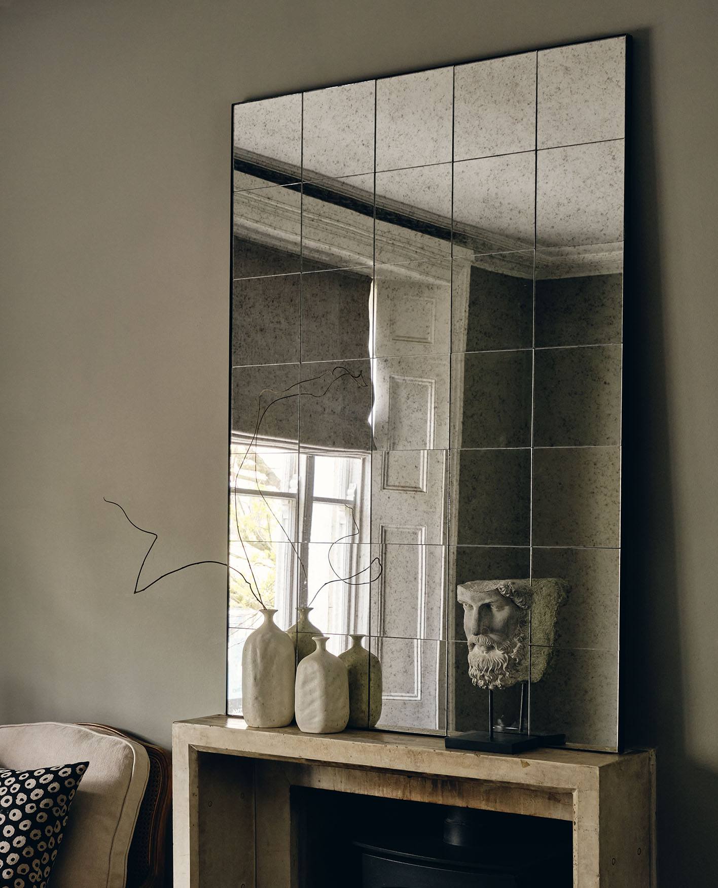 A large rectangular mirror with grid-style detailing sits on a console table.