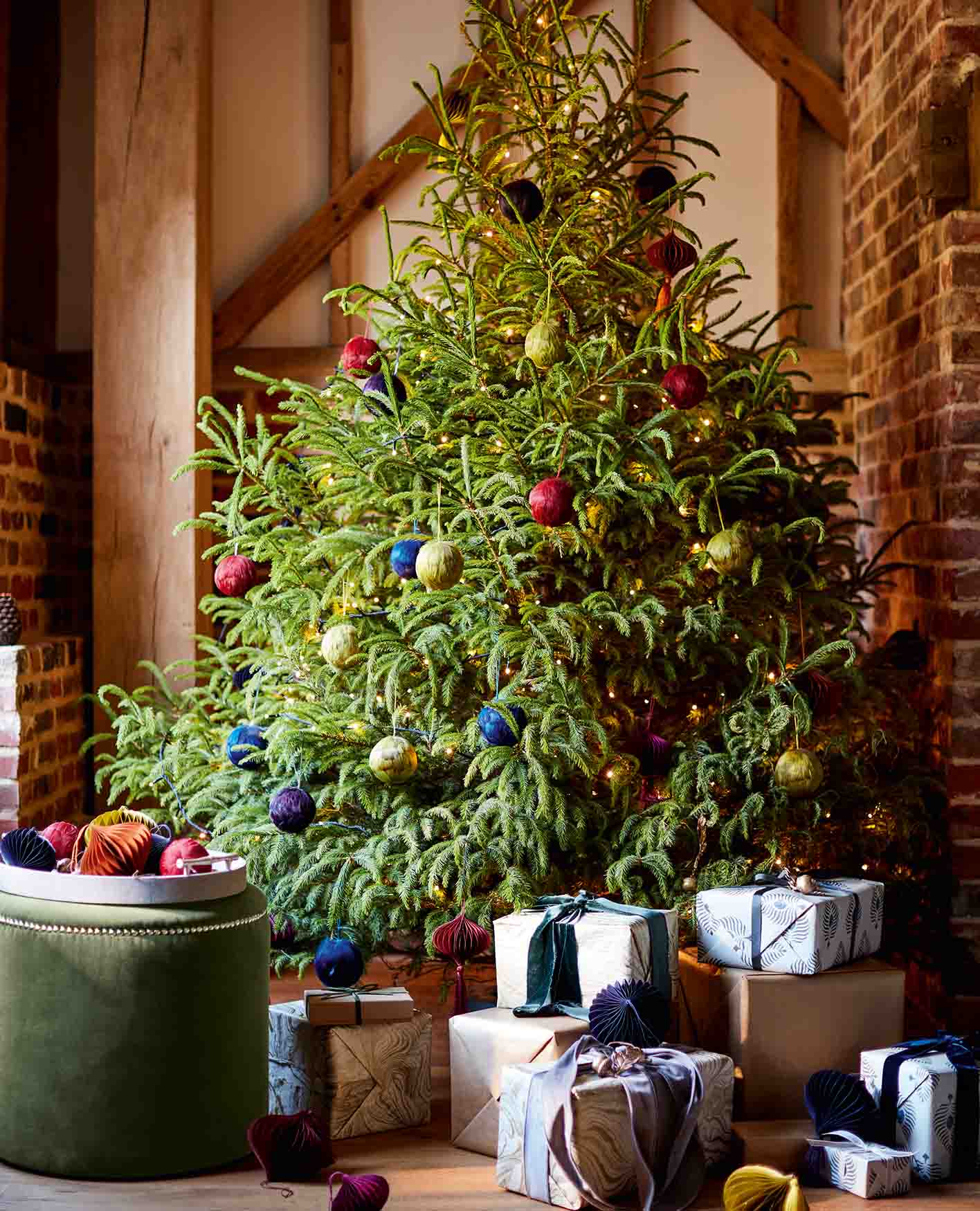 A blue sofa in a farmhouse style sitting room in front of a large tree decorated with baubles