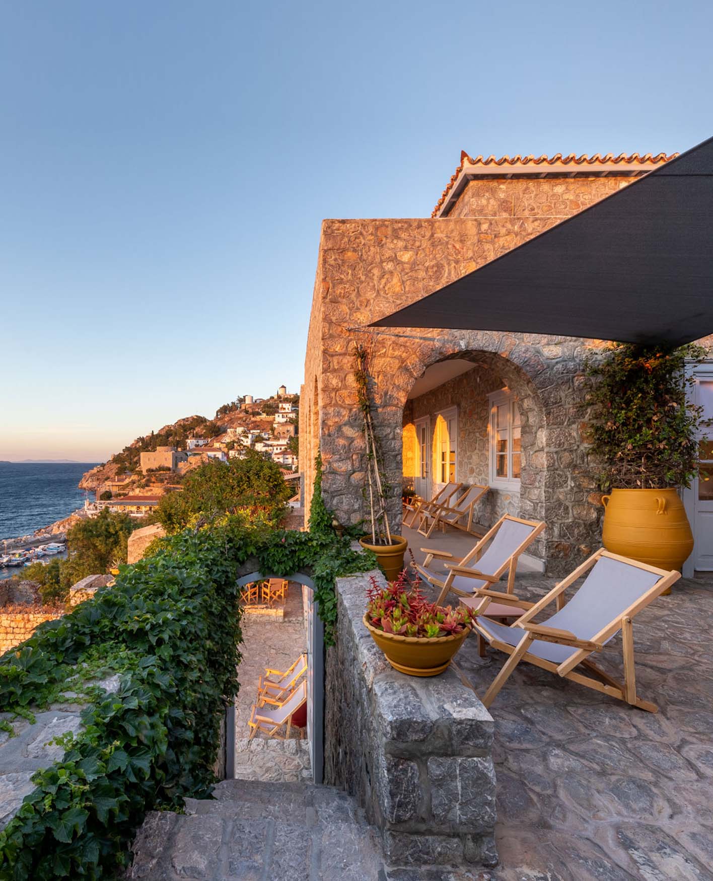 A coastal apartment in Greece with two deck chairs looking out over the sea.