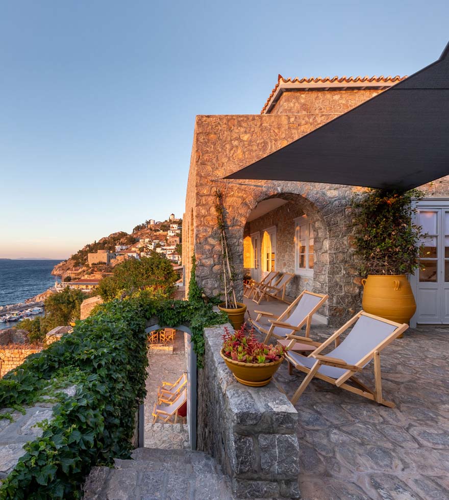 A coastal apartment in Greece with two deck chairs looking out over the sea.