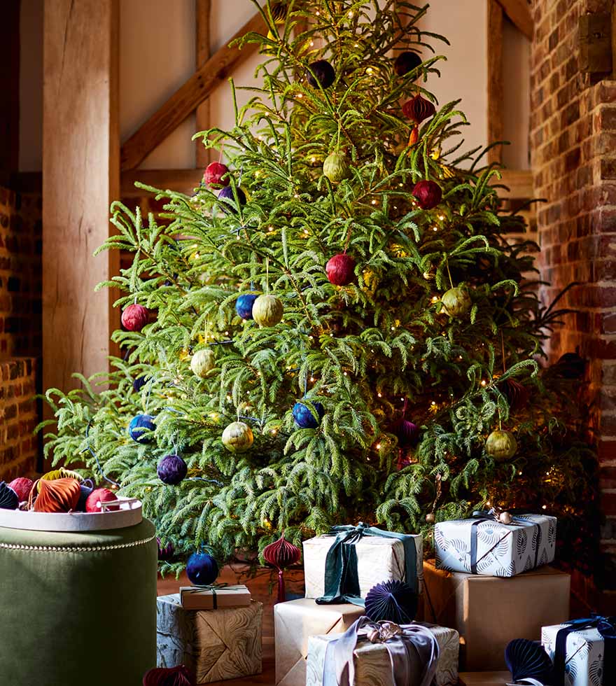 A blue sofa in a farmhouse style lounge in front of a large tree decorated with baubles