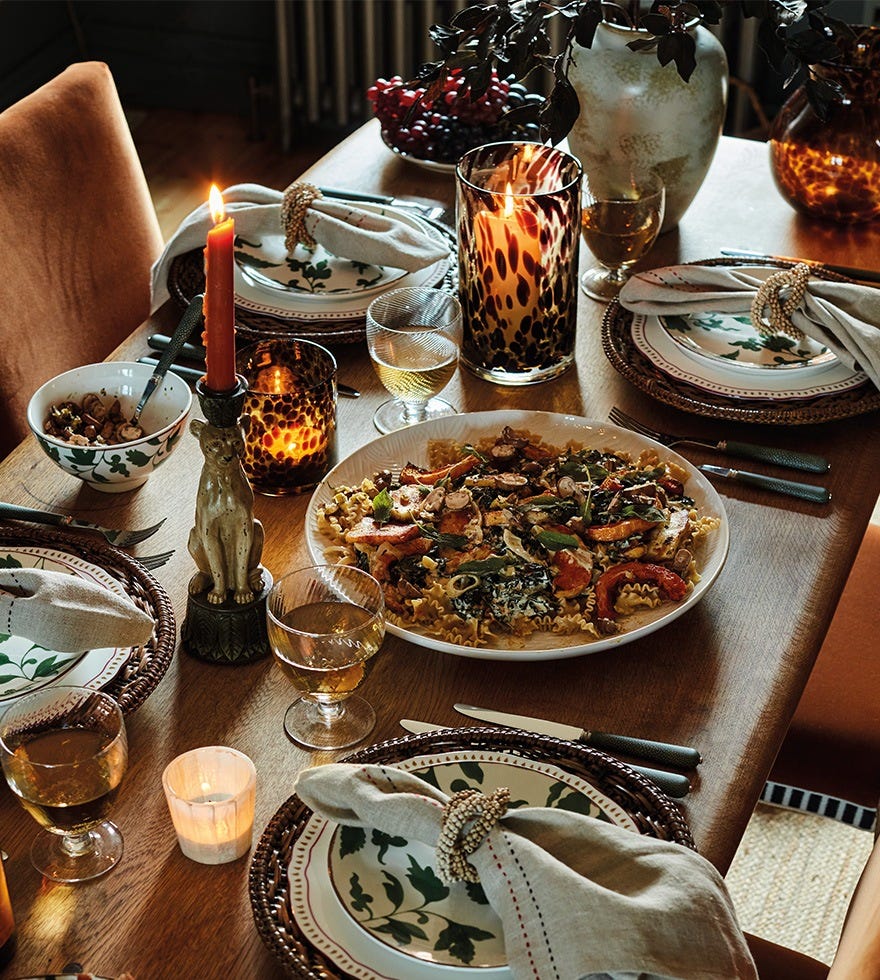 A dining table set with sharing dishes, candles and patterned tableware