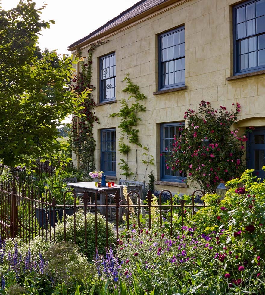 An outdoor furniture set sits in front of a stone-colored country house