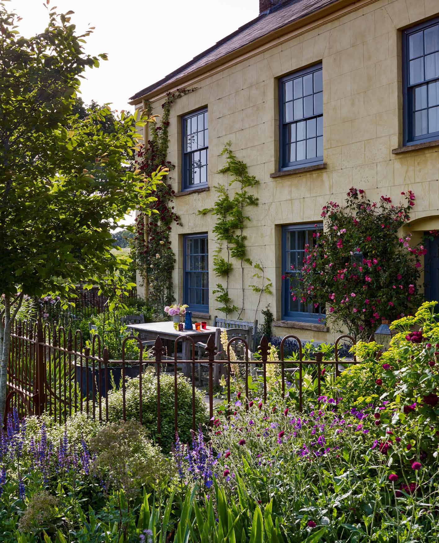 An outdoor furniture set sits in front of a stone-colored country house