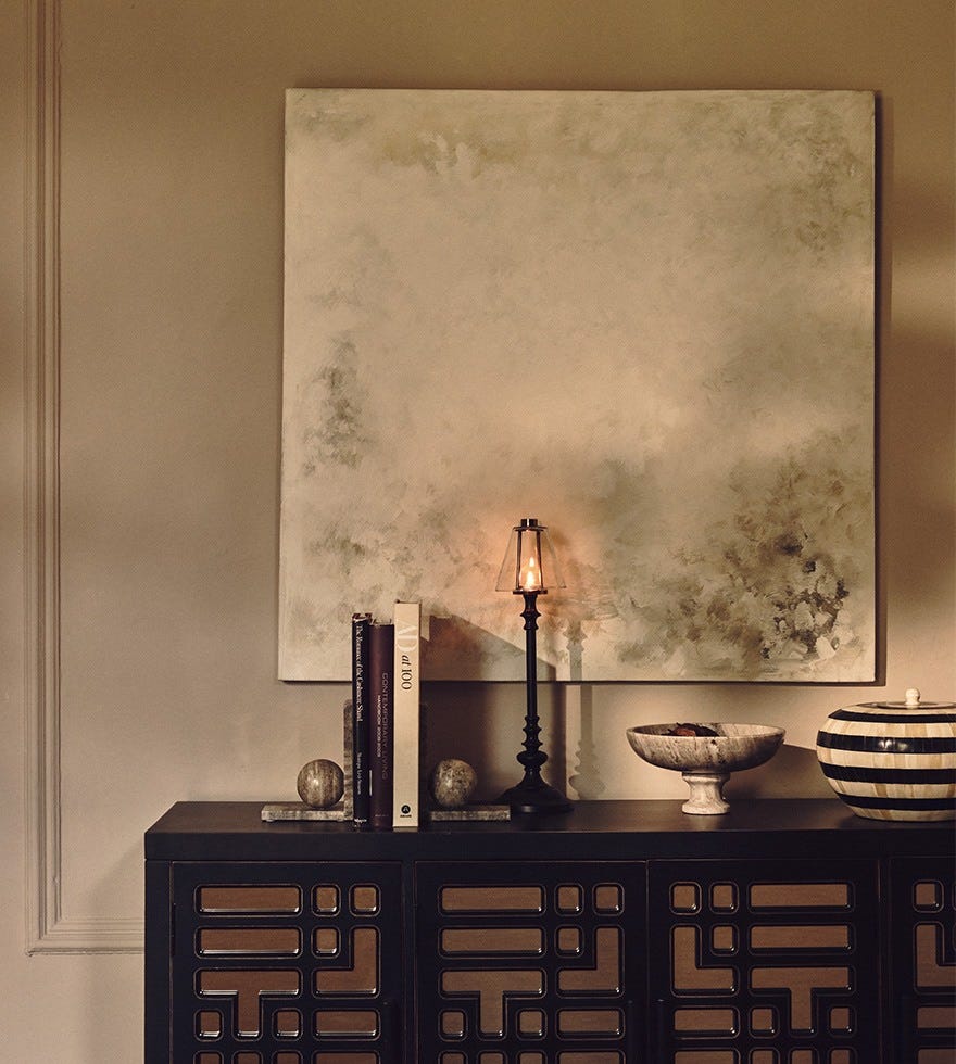 An abstract artwork of light colors hangs above a black sideboard decorated with monochrome decor pieces, including marble book ends.