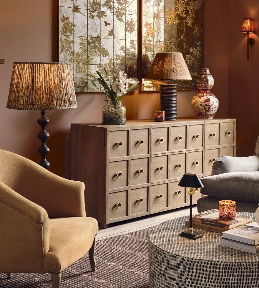 A cosy sitting room with a yellow armchair and wooden sideboard