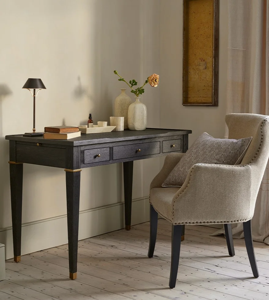 A black wooden desk with a herringbone linen armchair.