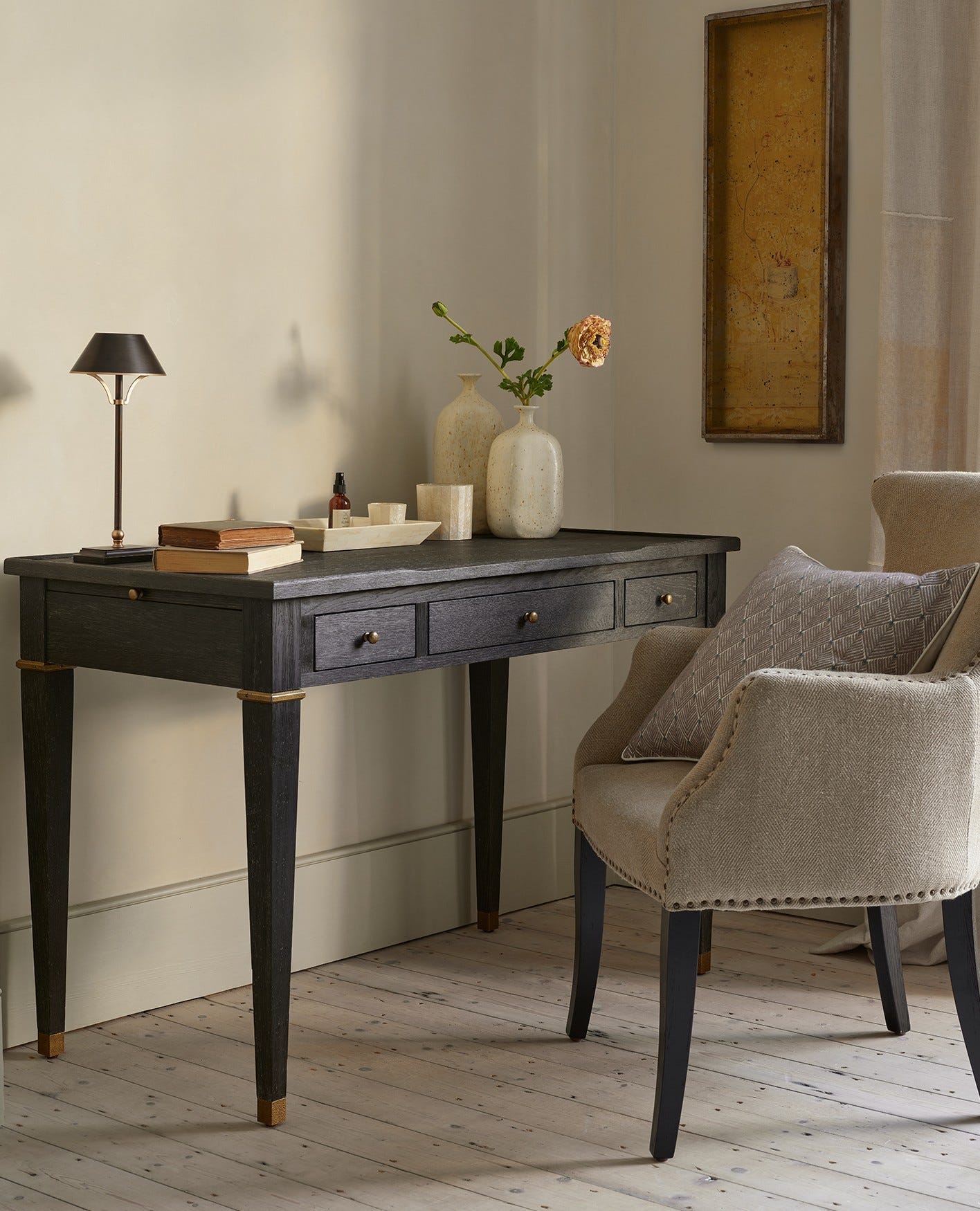 A black wooden desk with a herringbone linen armchair.