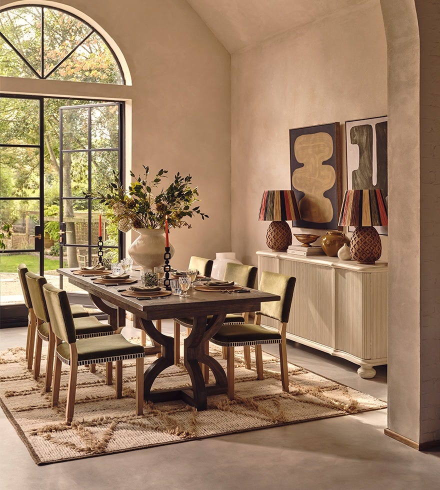 A dining table set up in a light and airy room with artwork on the walls.