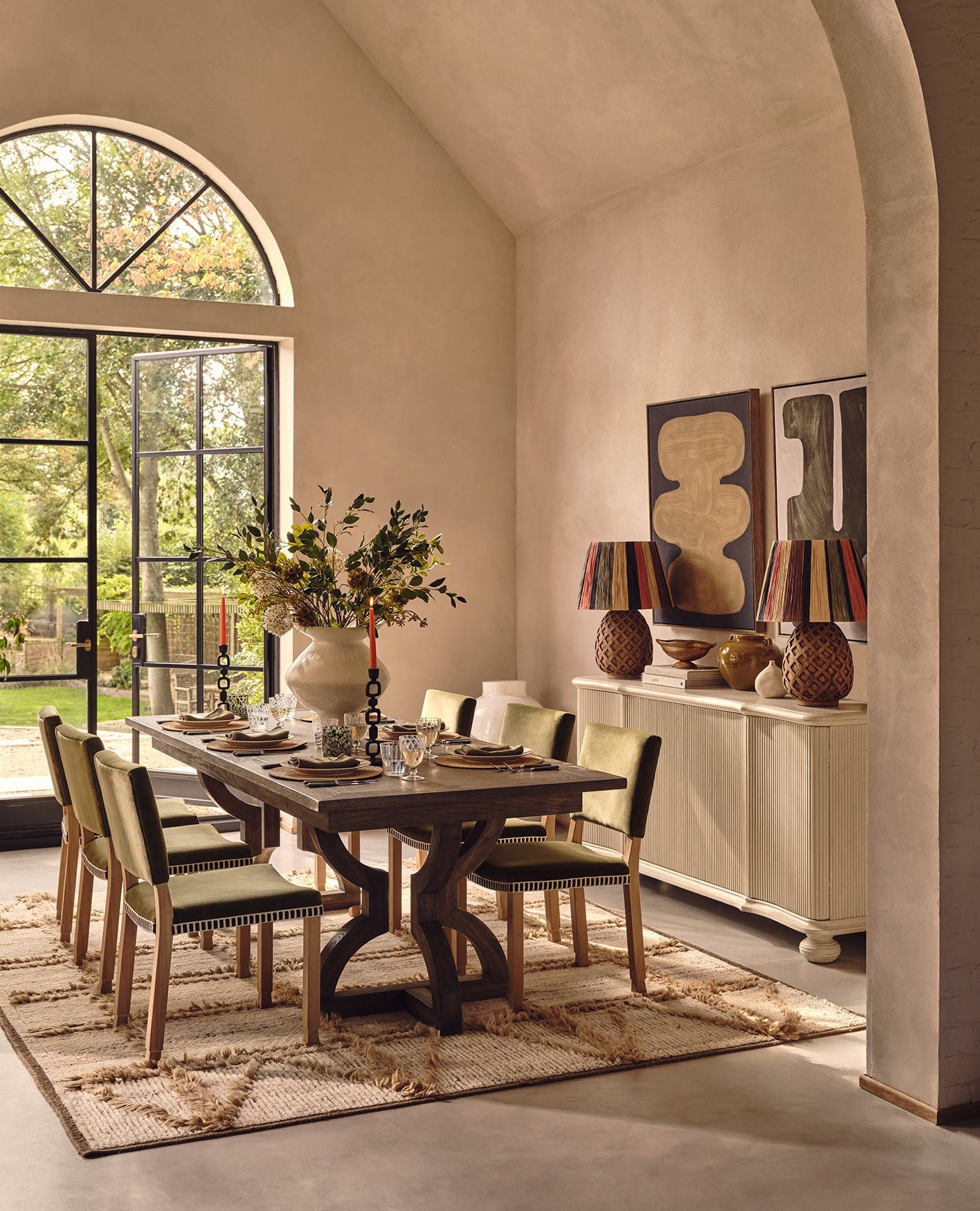 A dining table set up in a light and airy room with artwork on the walls.