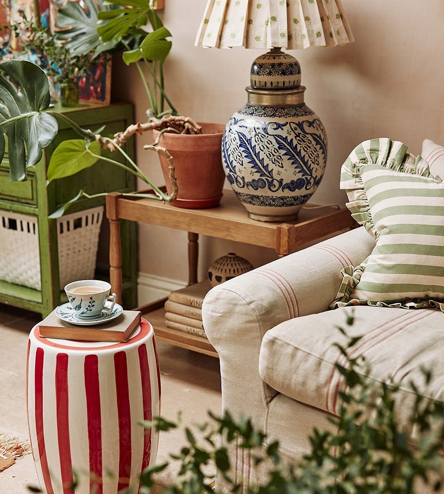 A teacup on a Rander stool surrounded by plants.