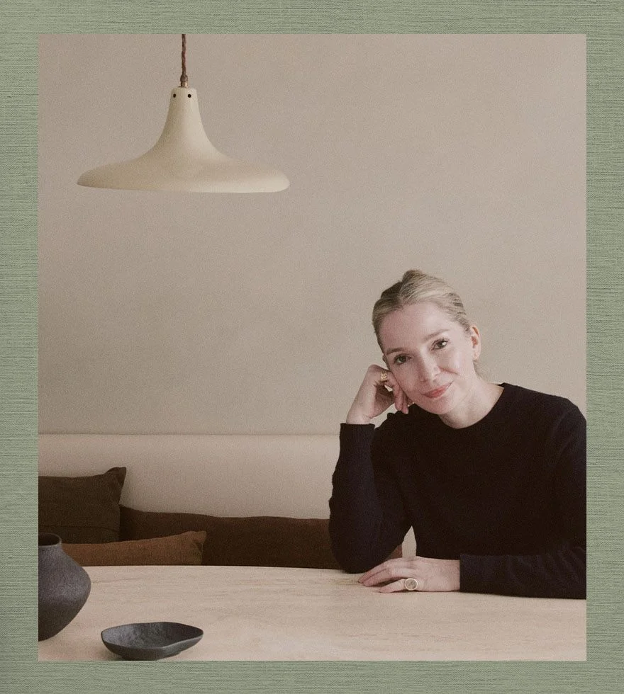 Louisa Grey, wearing a black long-sleeved top, sitting at a wooden table.