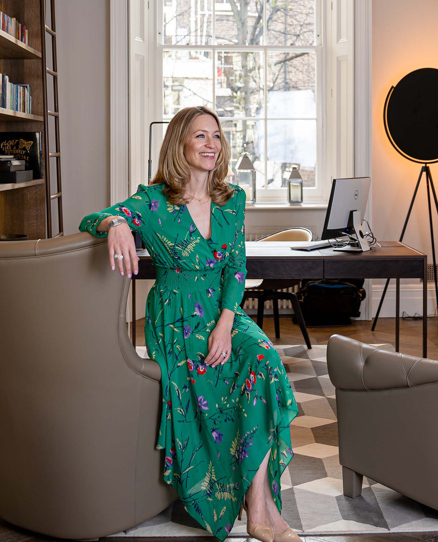 Jo Eccles wearing a green dress sat on a leather armchair