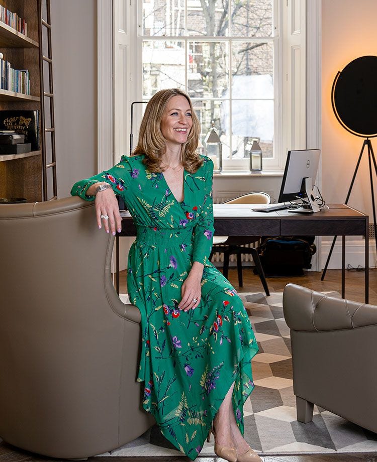 Jo Eccles wearing a green dress sat on a leather armchair