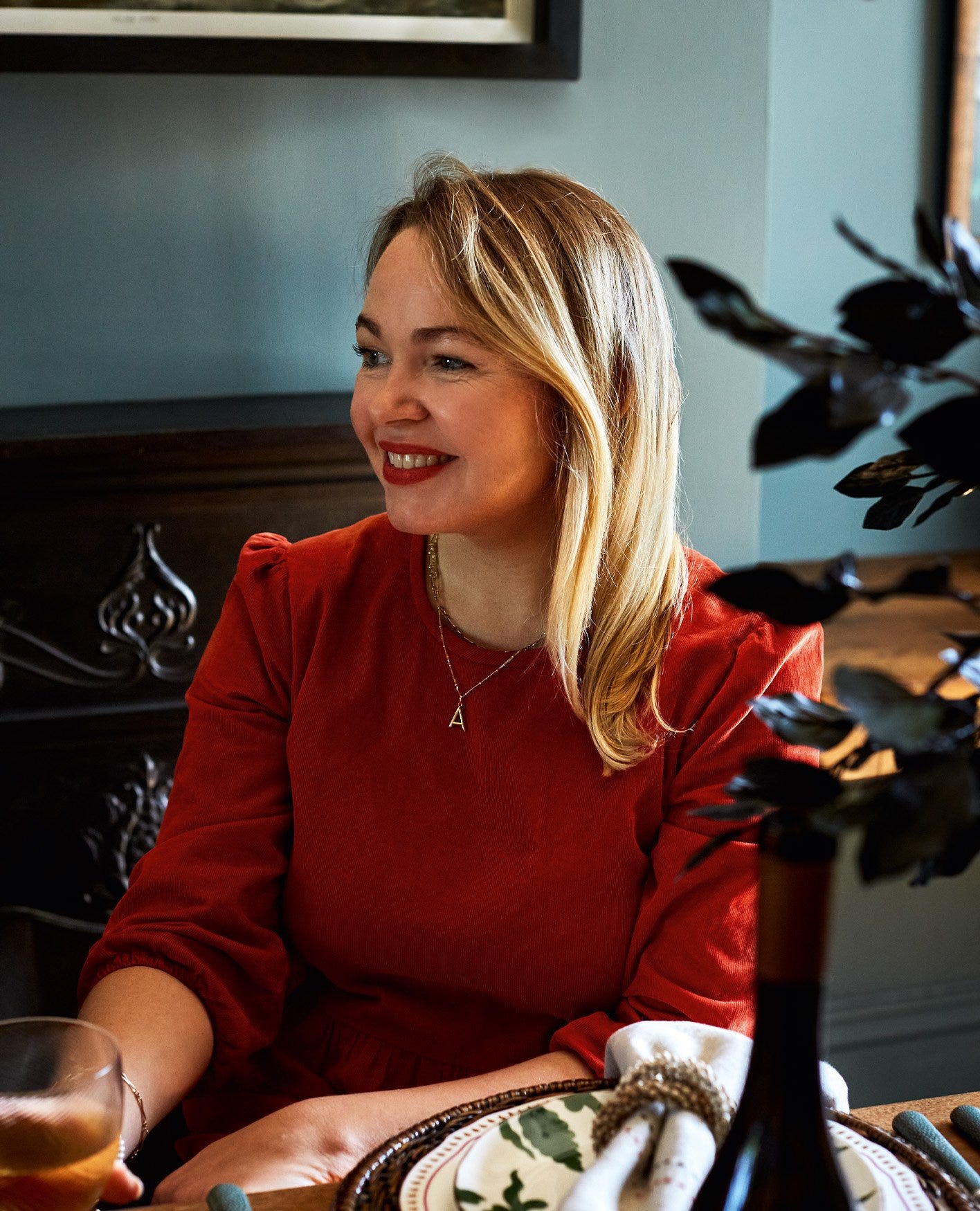 Rosie Birkett wears a red velvet dress and is smiling to someone off camera