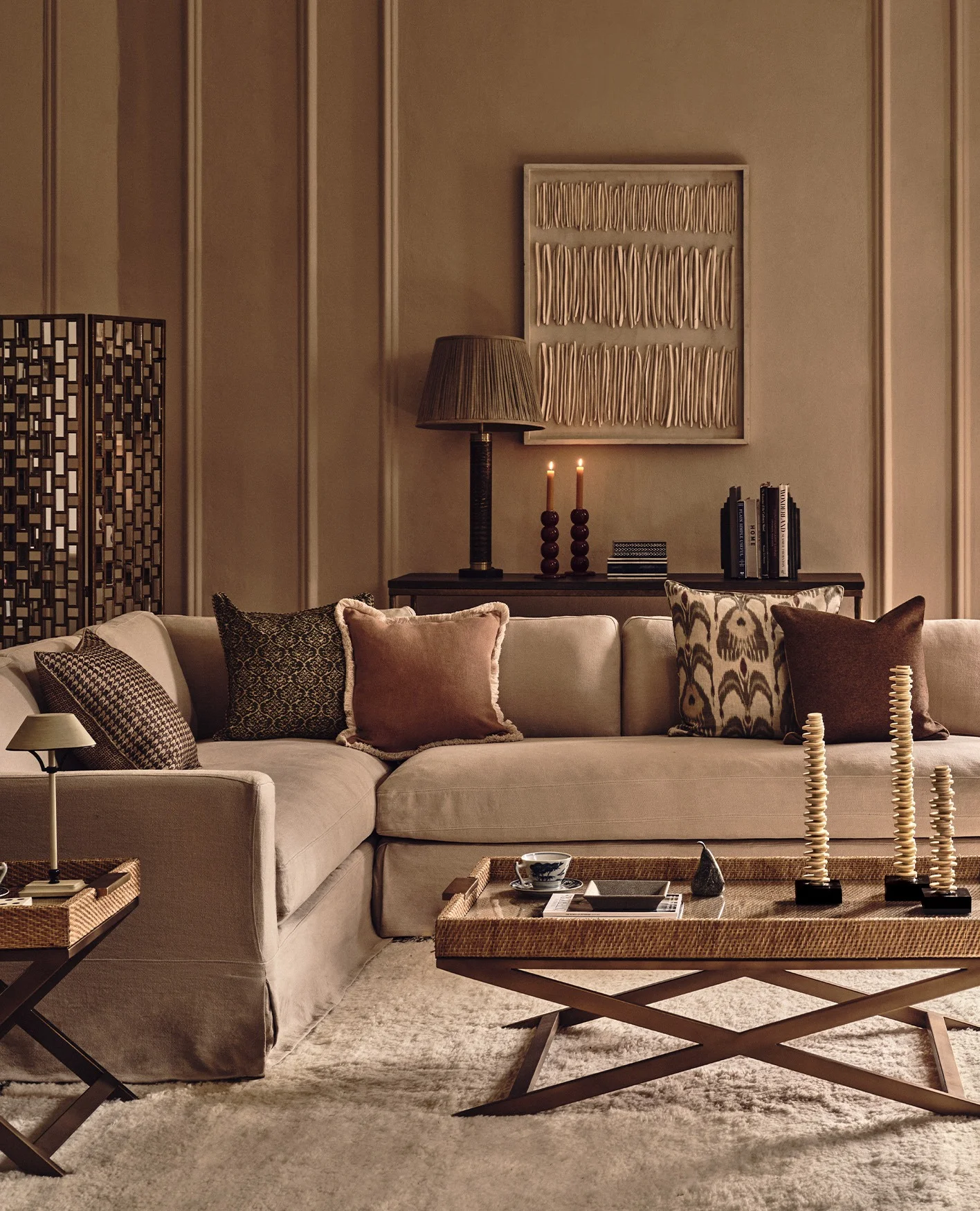 A cosy sitting room with a sofa dressed in lots of cushions in front of feature wall art.