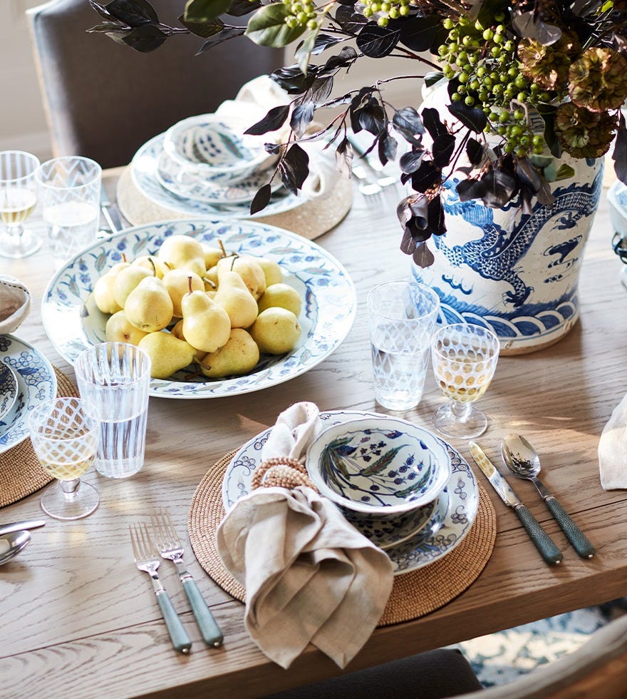 A summer tablescape featuring blue-and-white patterned crockery, patterned glassware and a bowl filled with lemons.