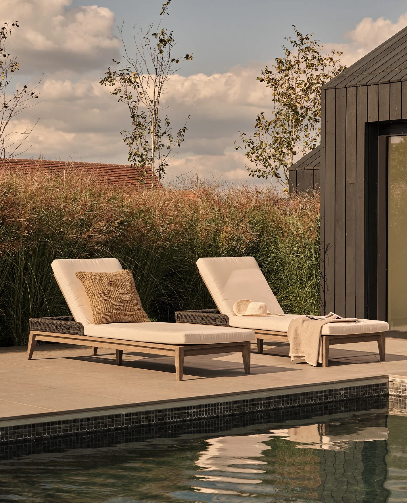 Two sun loungers are arranged alongside a swimming pool