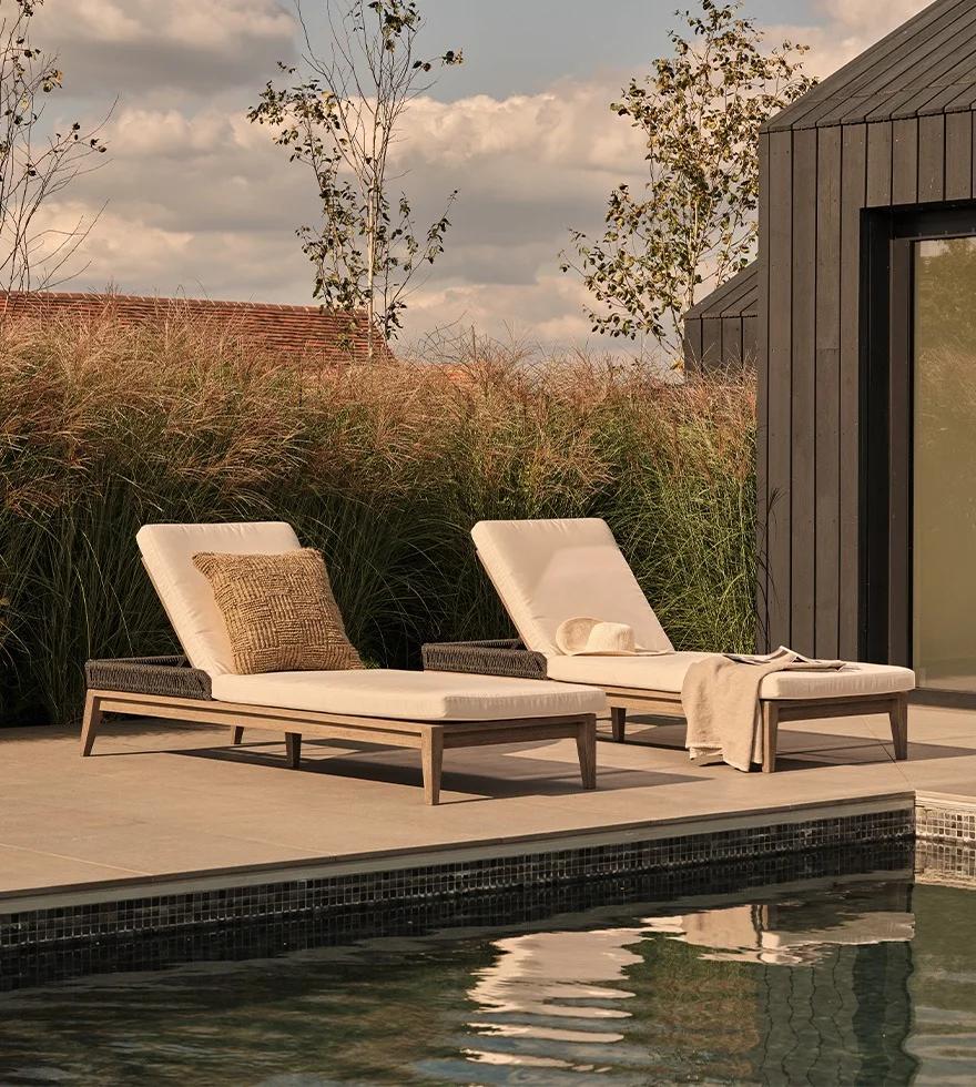 Two sun loungers are arranged alongside a swimming pool