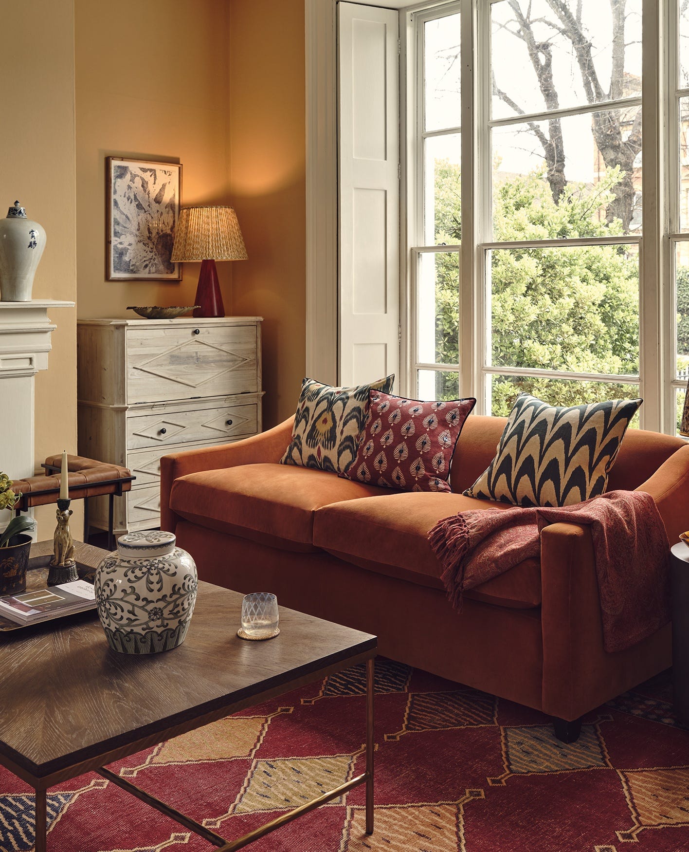 A cosy sitting room featuring an orange autumn sofa and patterned cushions