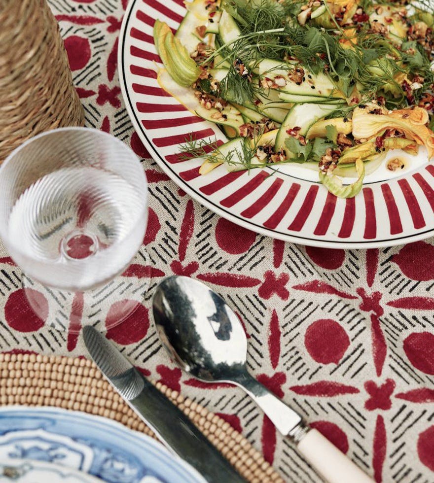 A courgette salad on a red Kintaro plate, with the Red Nostell Diamonds tablecloth beneath