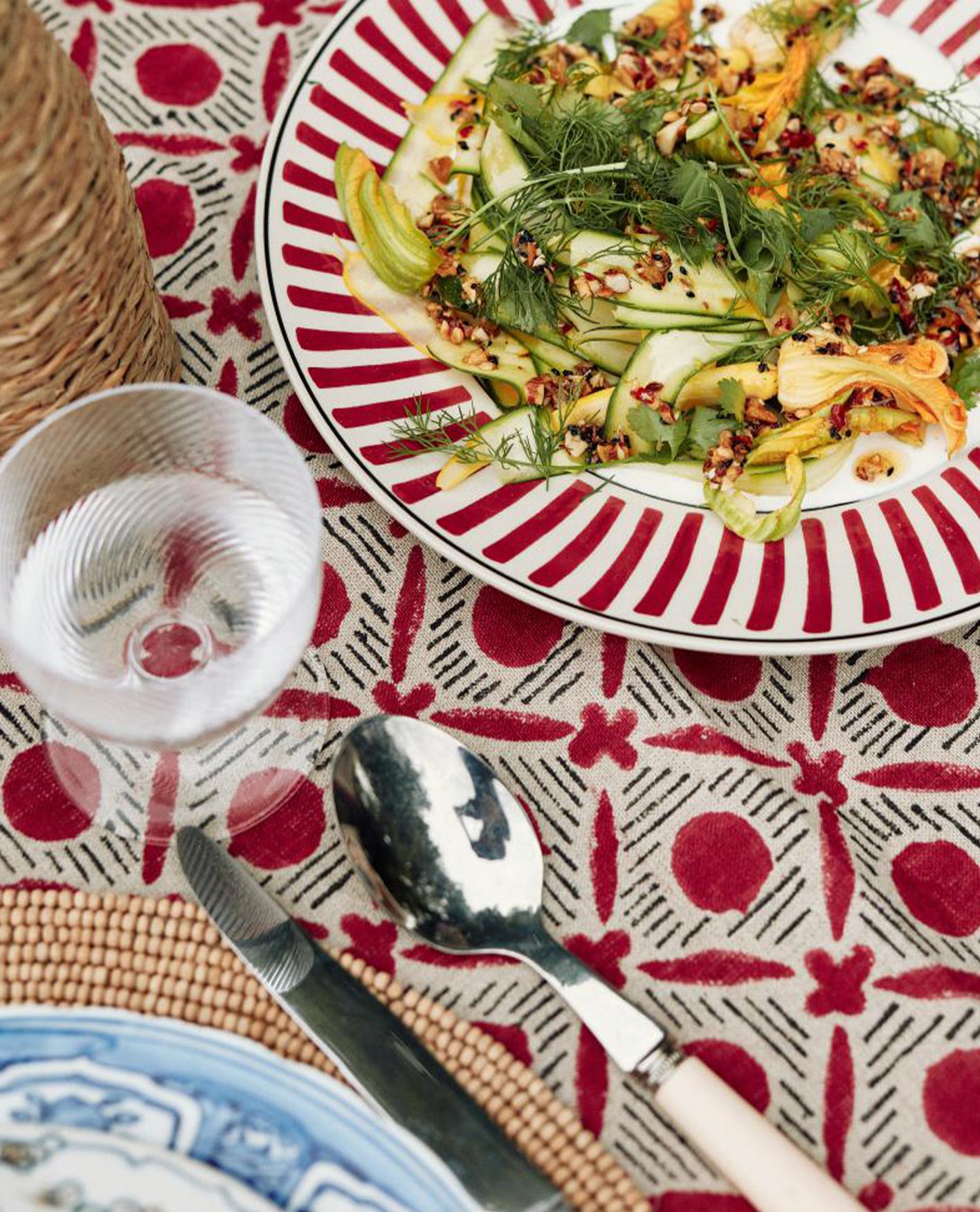 A courgette salad on a red Kintaro plate, with the Red Nostell Diamonds tablecloth beneath