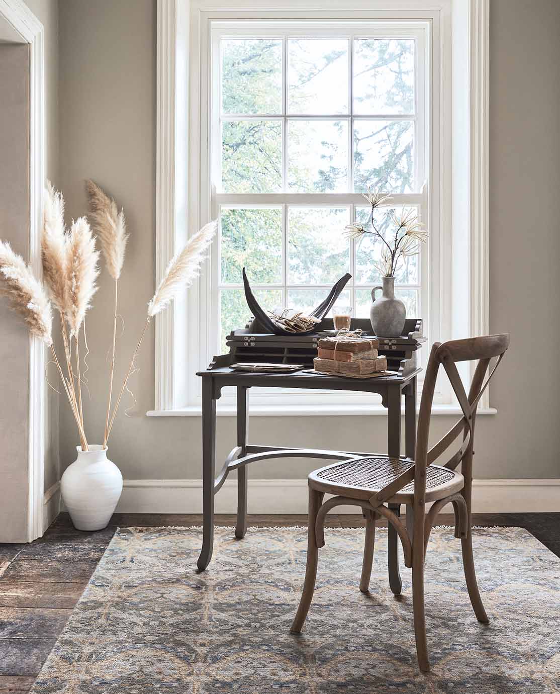 A wooden chair is pulled up to a small, wooden writing desk, which is decorated with ornaments.