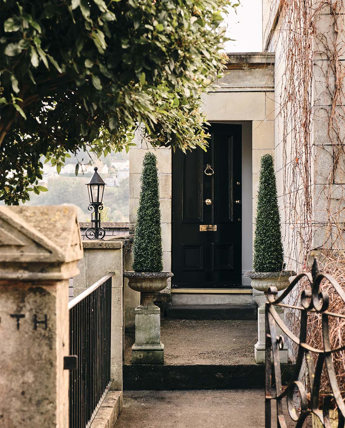 The exterior of a traditional Bath townhouse, with honey-coloured stone and a black front door