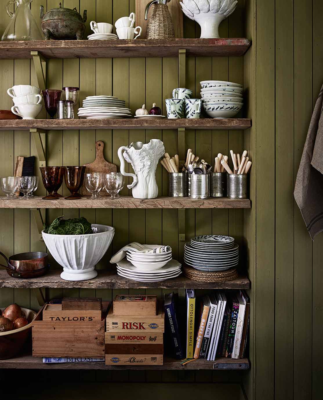 Green shelving with a mixed of white crockery and cutlery