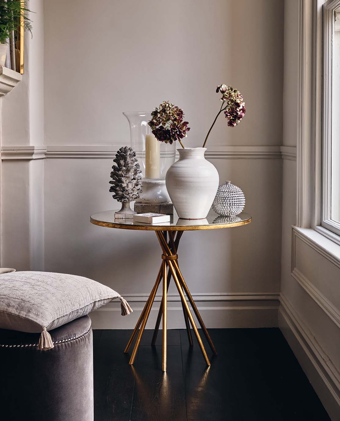 A gold and mirrored side table with twisted legs is decorated with nature-inspired ornaments