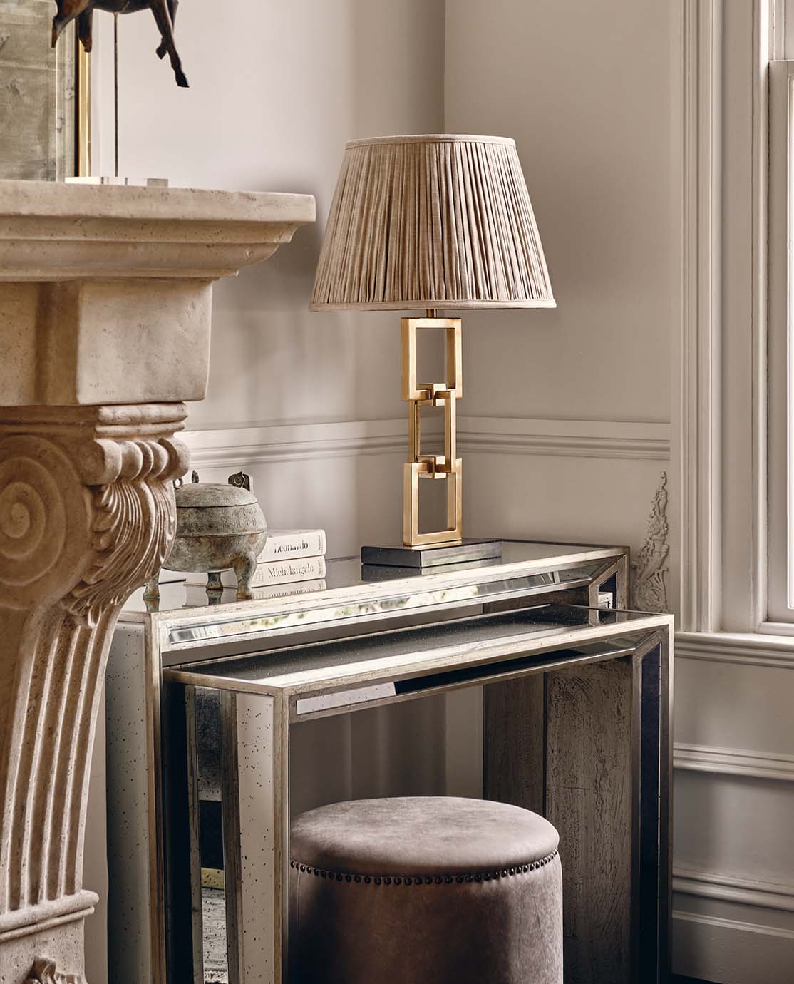 Two mirrrored nest tables, with a gold lamp and pleated lampshade