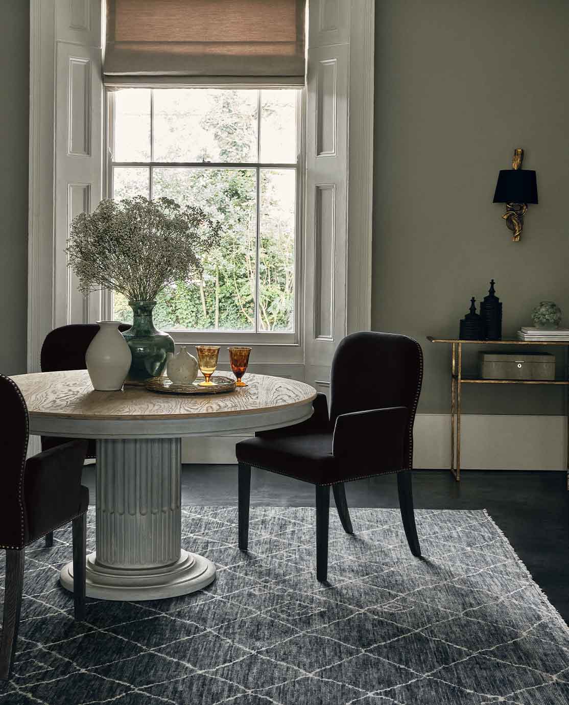 A rattan armchair in front of a black desk, decorated with a monochrome abstract print