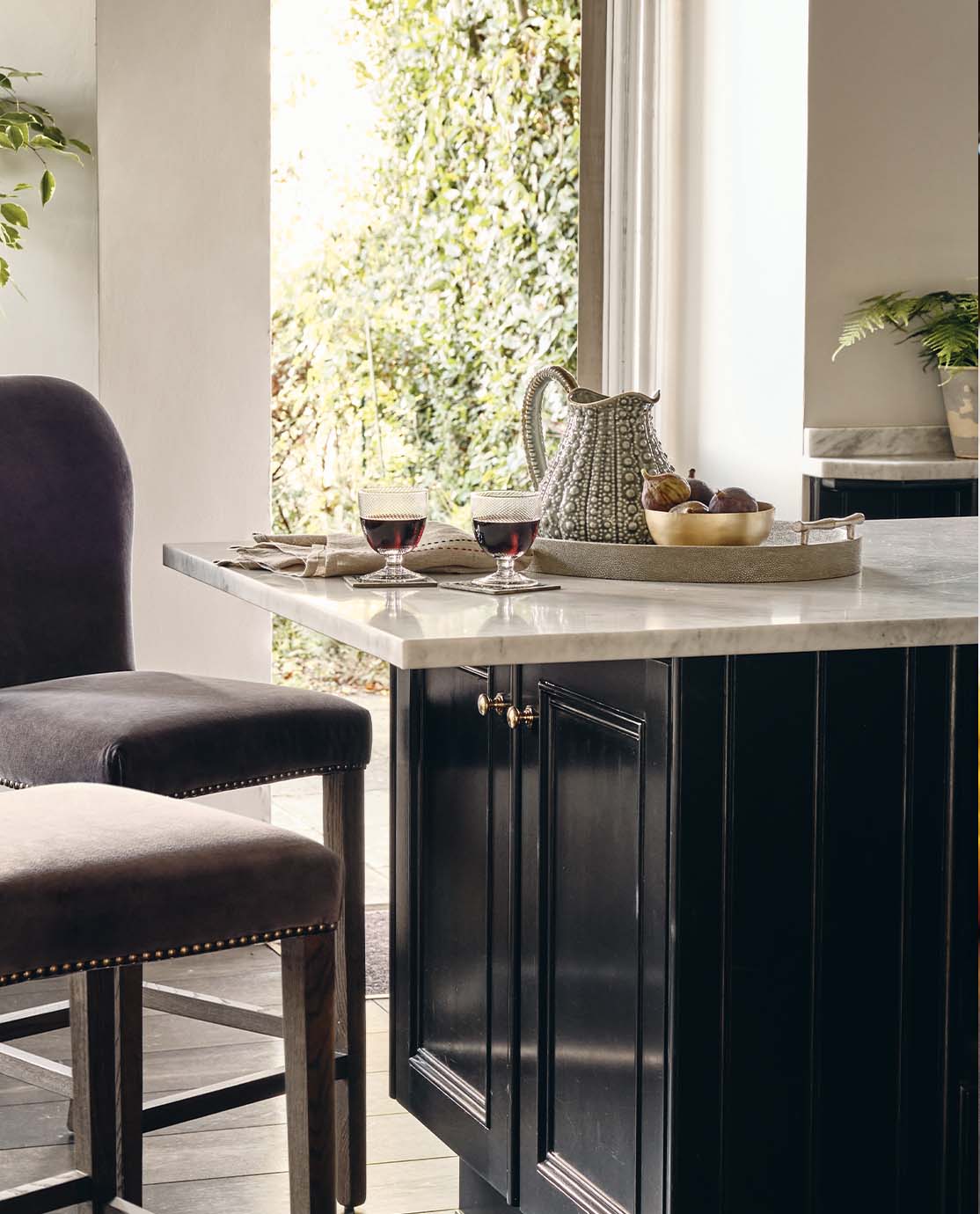 Two velvet bar stools sit up against a marble-topped kitchen counter