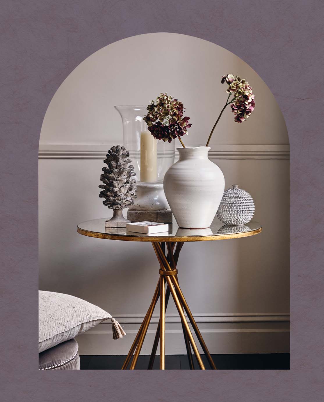 A gold and mirrored side table with twisted legs is decorated with a white vase and candles