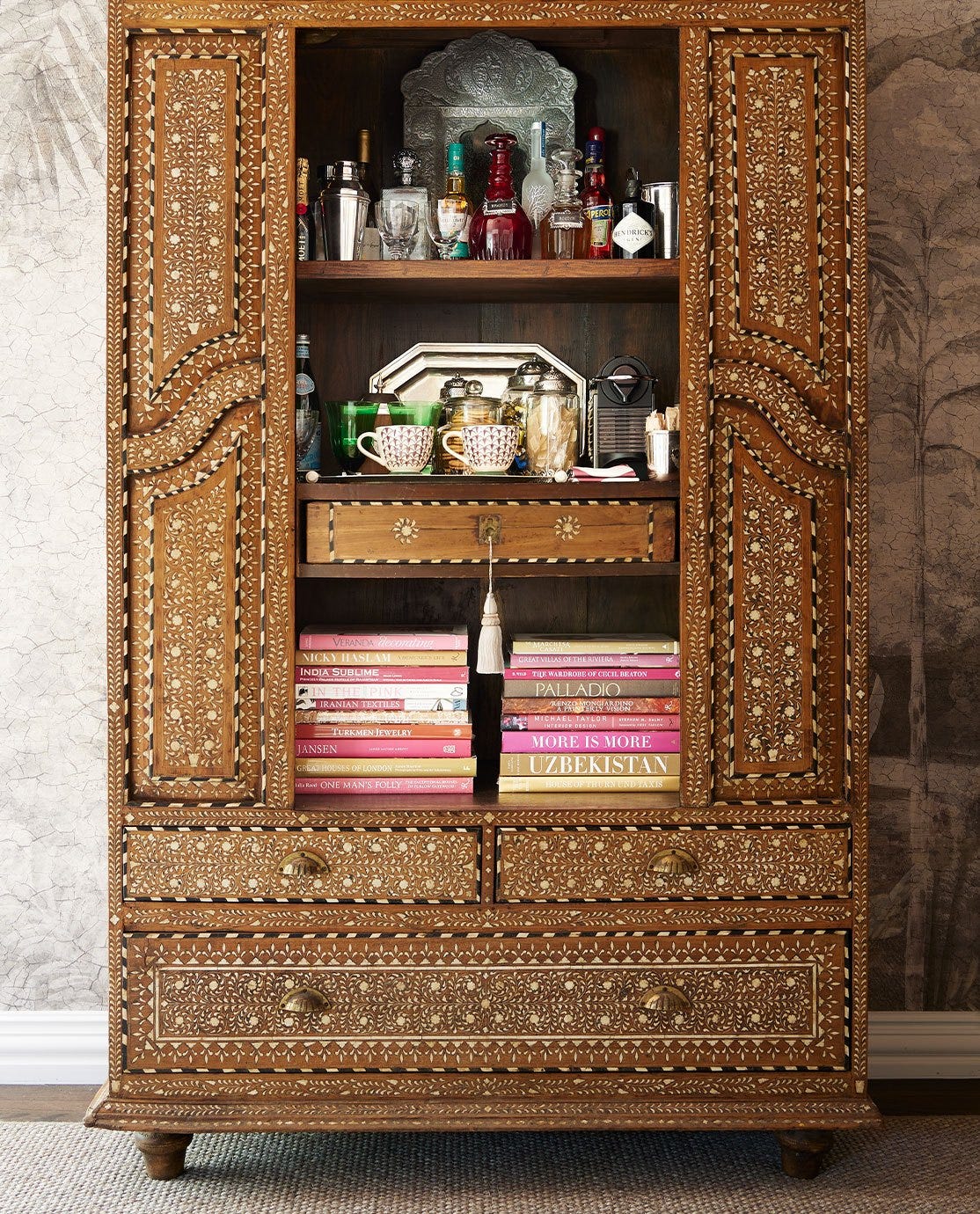 A rattan armchair in front of a black desk, decorated with a monochrome abstract print