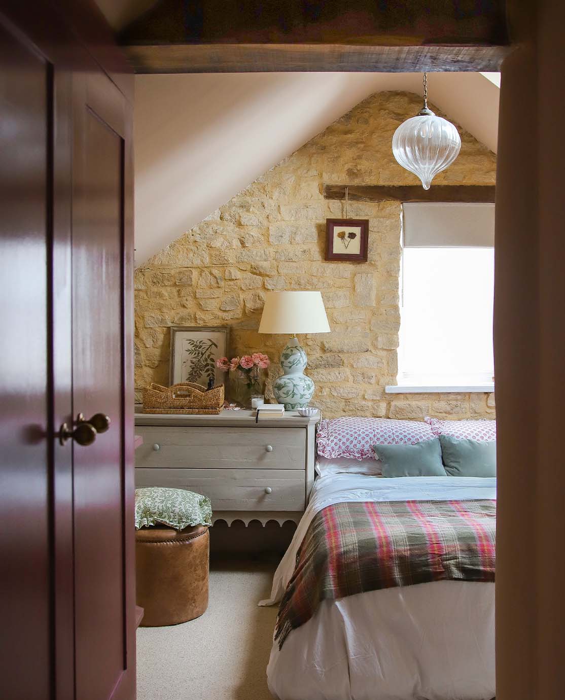 A cozy cottage bedroom with limestone walls, wooden beams and colorful interiors