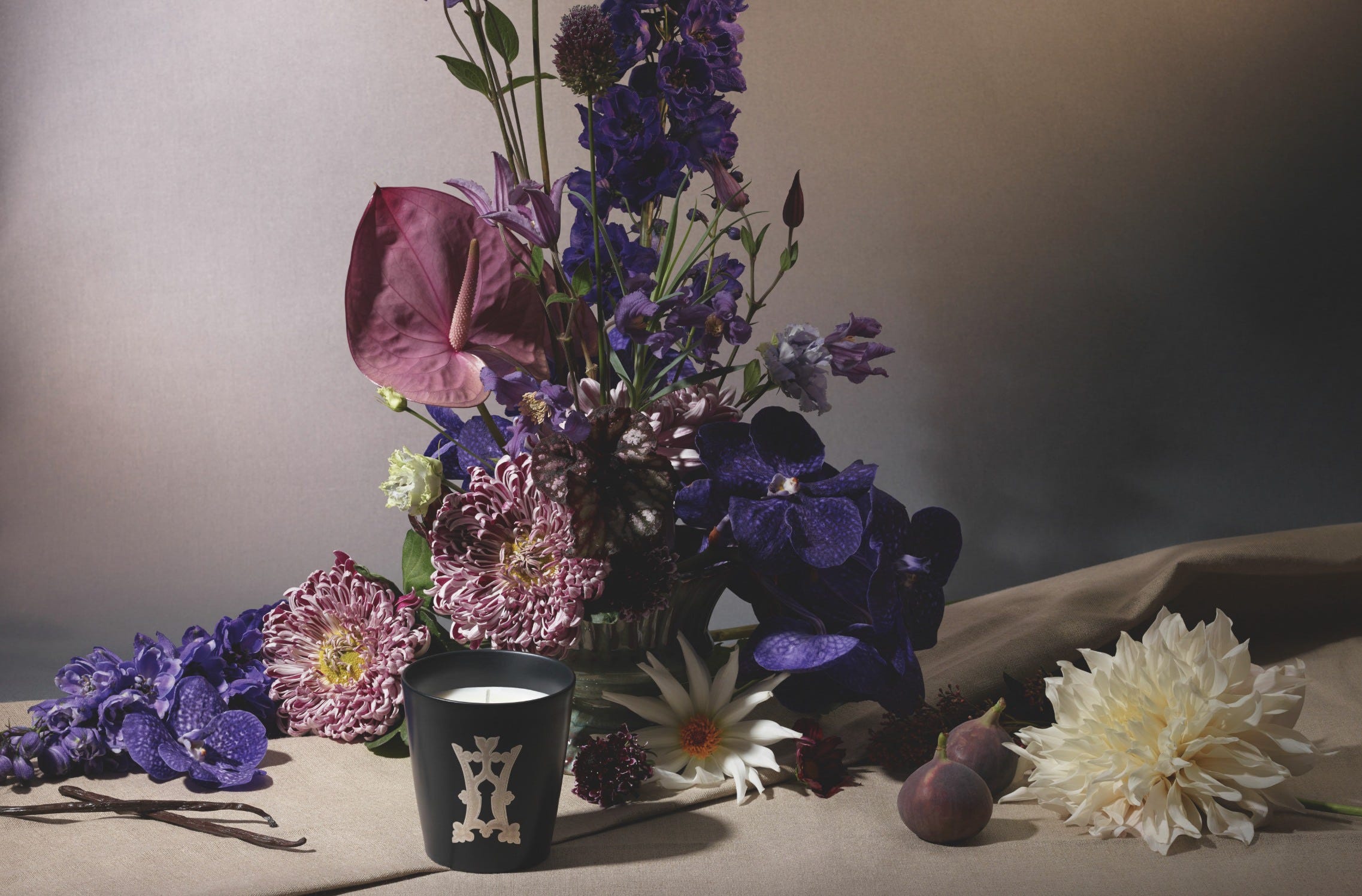 Clair de Lune candle in front of a bouquet of purple and pink flowers