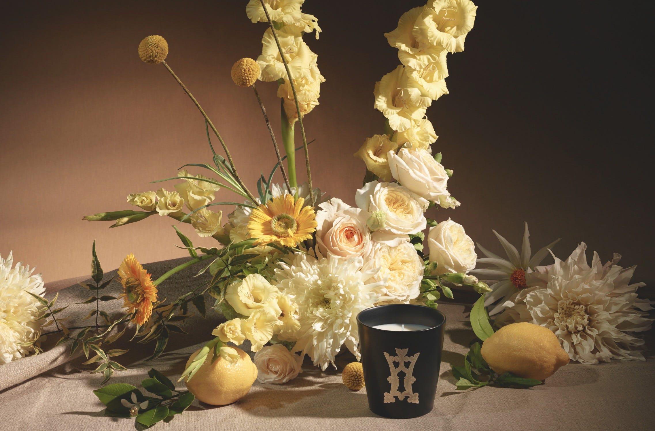 Herbes de Montagne candle in front of a bouquet of yellow and white flowers