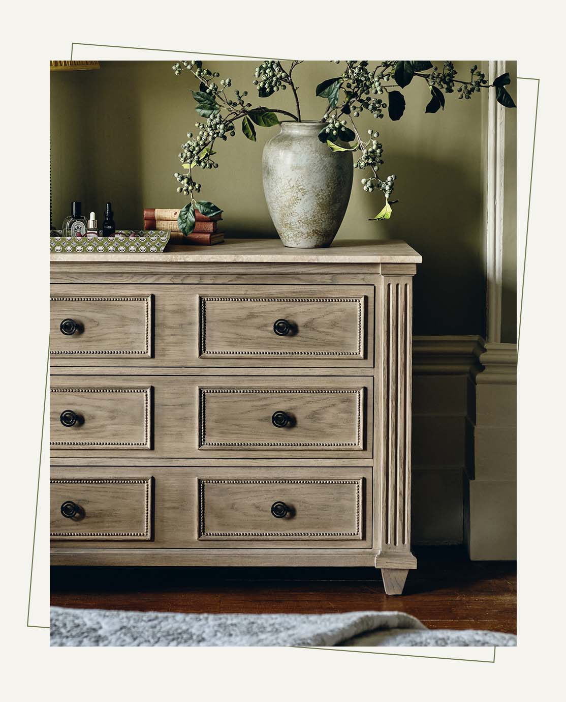 Chest of drawers A wooden chest of drawers with ornate edging and black handles. A white vase holding faux berries sits on top.