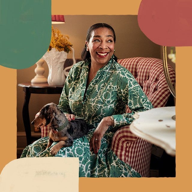 Paula Sutton is sitting in a red and white gingham chair with a small dog in her lap