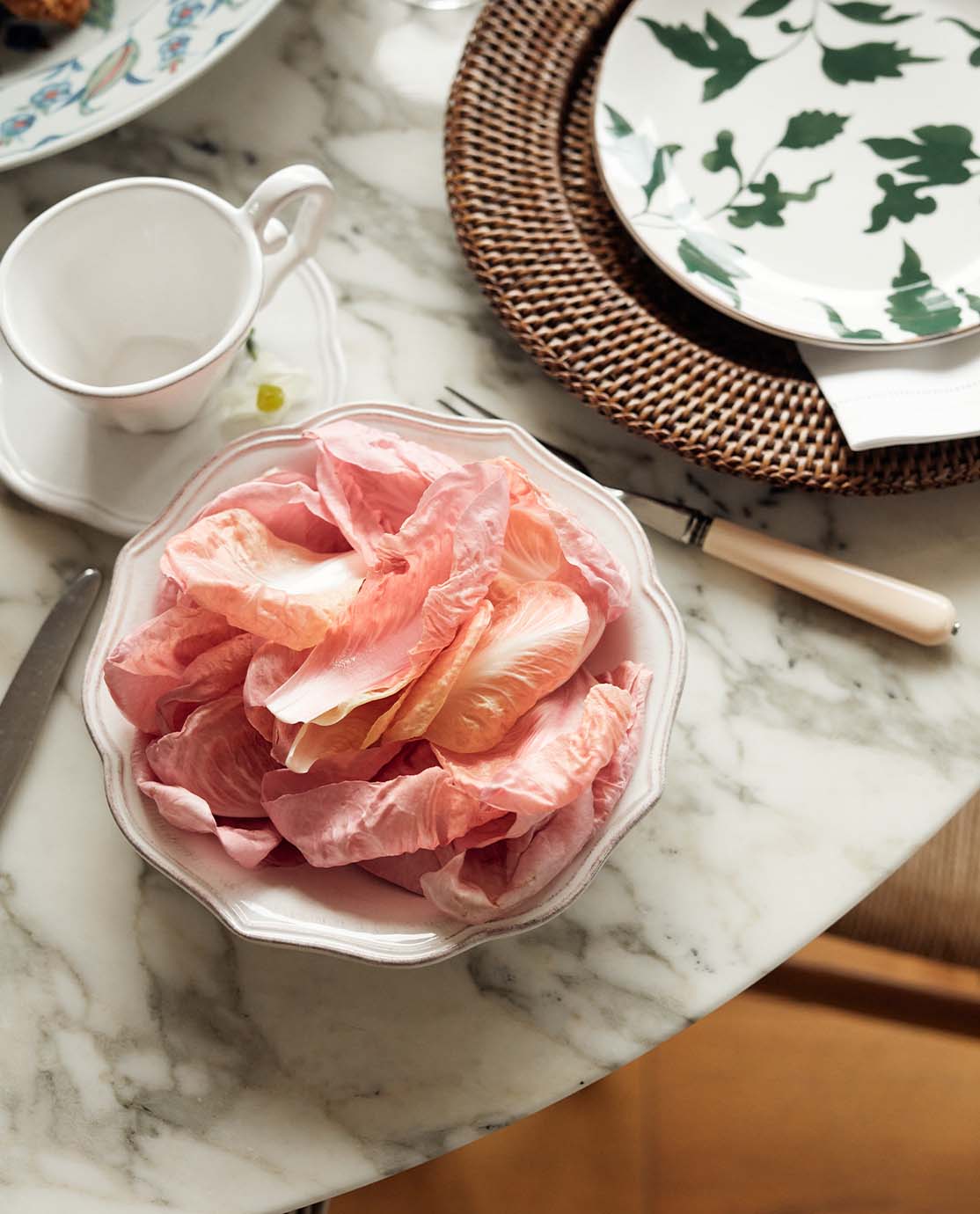 A bowl of pink Radicchio leaves on a marble table.